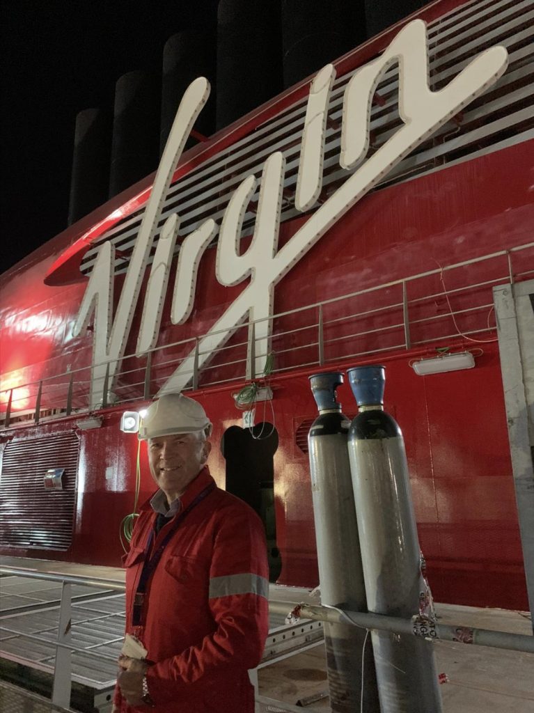 virgin voyages cruiser and man in front